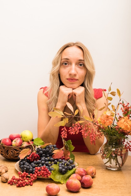 La nutritionniste de fille s'assied à une table avec des légumes