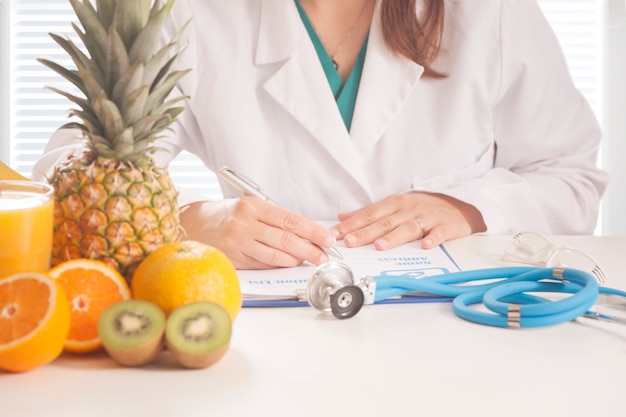 Nutritionniste rédigeant des dossiers médicaux et des ordonnances avec des fruits frais