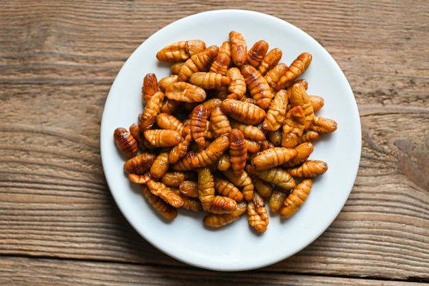 Nymphe sur fond de plaque blanche frire les vers à soie chrysalide frite pour le ver du coléoptère alimentaire