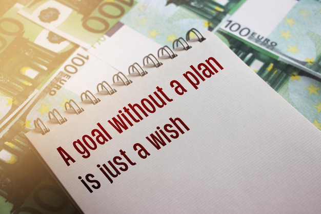 Un objectif sans plan n'est qu'un souhait sur la page des cahiers portant sur des factures de 100 euros Définition d'objectifs personnels concept de coaching d'entreprise