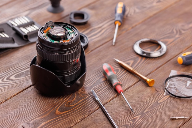 Objectif zoom de caméra à moitié démonté sur une table en bois entourée d'outils