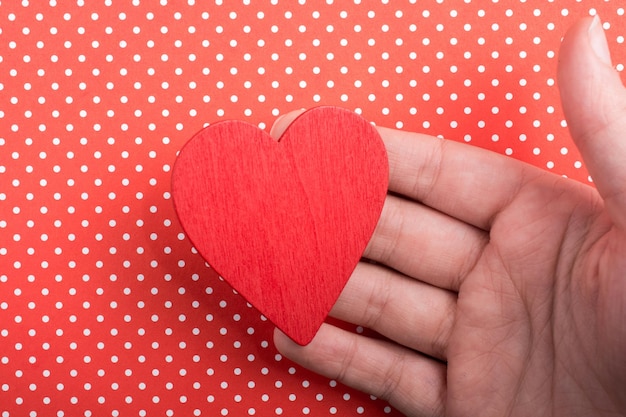 Objet en forme de coeur de couleur rouge à la main sur du papier pointillé