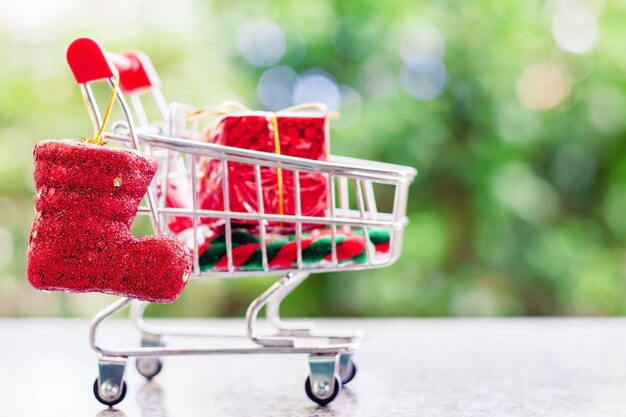 Objets de décoration de Noël dans un mini-caddie ou un chariot contre un dos vert naturel flou