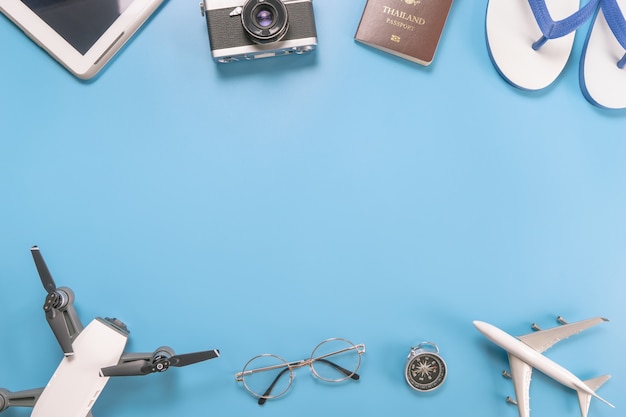 Objets et gadgets de voyage en été sur fond bleu avec espace de copie central