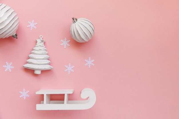 Objets d'hiver de composition simplement minimale ornement boule sapin traîneau isolé sur fond tendance pastel rose. Noël Nouvel An décembre pour le concept de célébration. Espace de copie de vue de dessus à plat