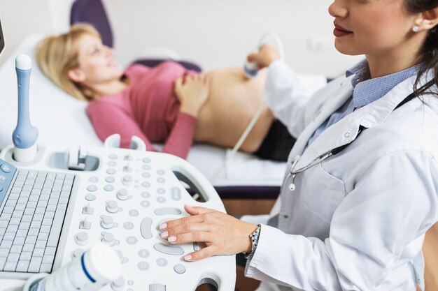 Obstétricien examinant le ventre de femme enceinte par échographie.