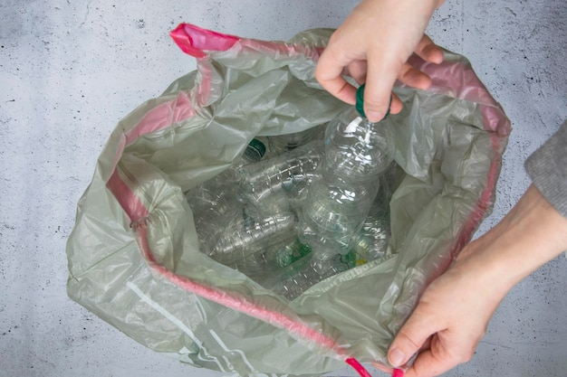 Obtenir à la main des bouteilles en plastique à jeter dans un sac poubelle prêt à recycler le plastique de gestion des déchets