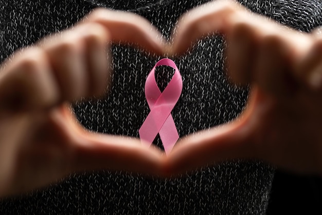 Octobre Mois de la sensibilisation au cancer du sein, une femme adulte portant un t-shirt foncé avec un ruban rose à la main pour soutenir les personnes vivant et malades. Concept international de la femme, de la mère et de la journée mondiale du cancer.