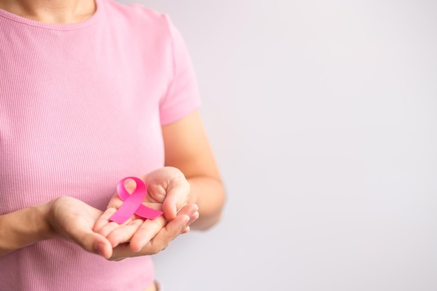 Octobre rose Mois de la sensibilisation au cancer du sein femme main tenir un ruban rose et porter une chemise pour soutenir la vie et la maladie des personnes Mois national des survivants du cancer Concept de la journée mondiale du cancer et de la mère