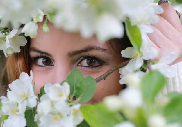 Oeil de fille derrière la fleur d'arbre