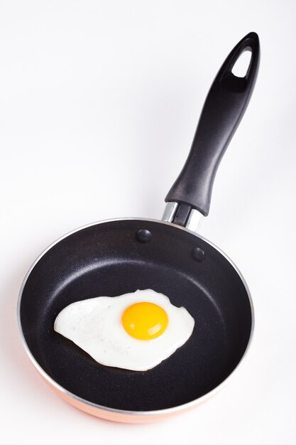 Un œuf au plat sur une poêle en téflon sans huile isolé sur blanc