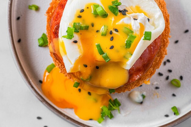 Oeuf bénédicte Oeuf poché jambon sauce hollandaise oignon sur tranche de pain grillé pour un délicieux petit déjeuner vue de dessus