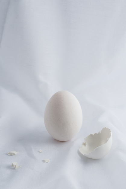 Photo oeuf blanc et coquille d'oeuf sur tissu blanc