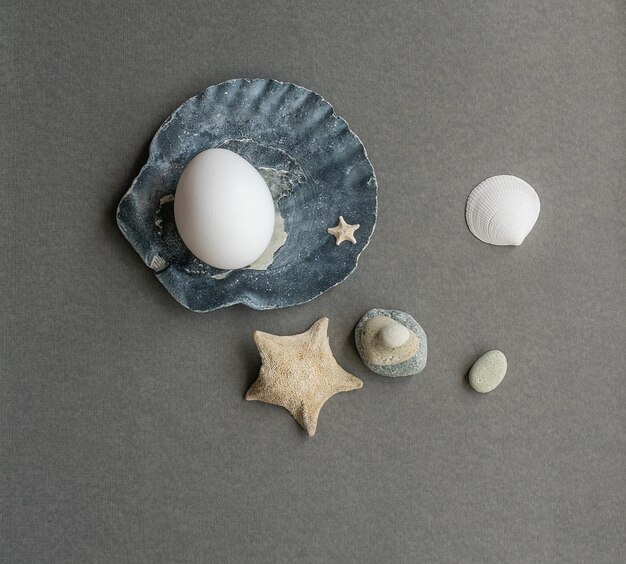 Oeuf blanc dans une composition de Pâques avec des étoiles de mer et des bâtons de la mer