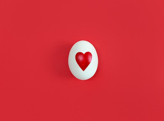 Oeuf blanc avec forme de coeur sur rouge