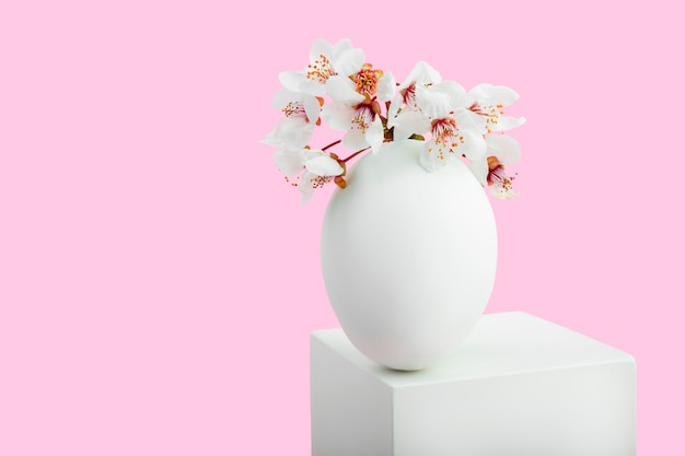 Oeuf blanc et formes géométriques blanches avec des fleurs de sakura sur fond rose