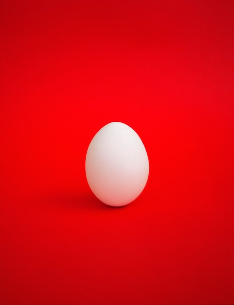 Un œuf blanc sur une surface rouge