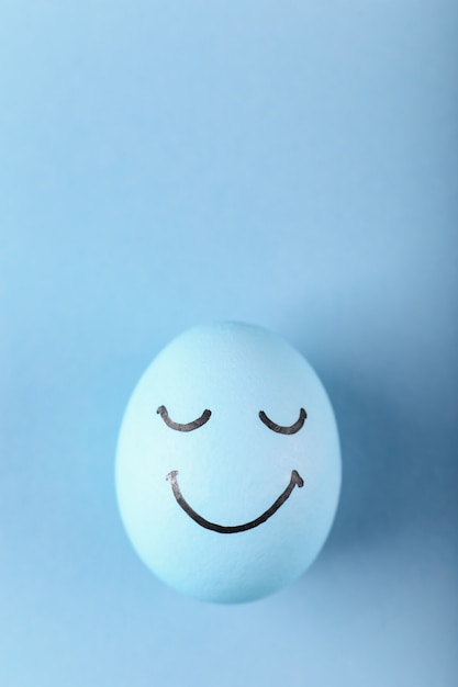 Oeuf bleu avec des sourires peints Carte de voeux joyeuses Pâques.