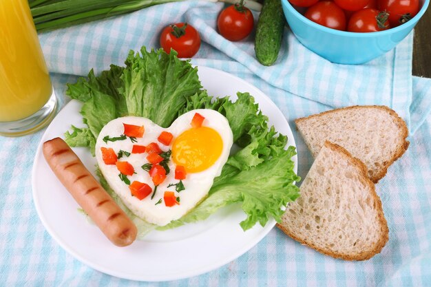 Oeuf brouillé avec saucisse et légumes servi dans une assiette sur fond de tissu