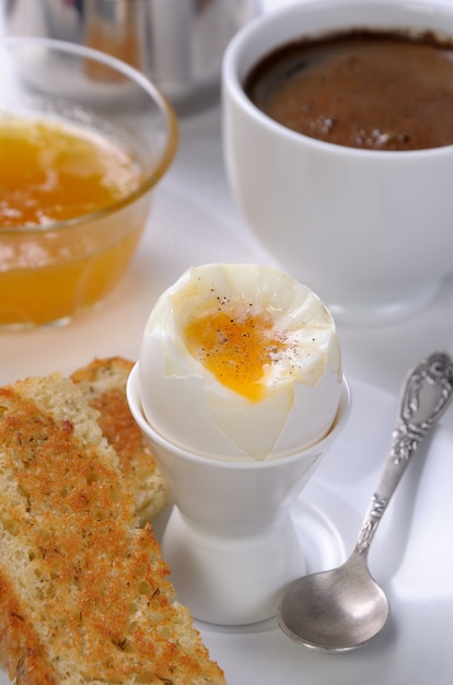 Oeuf à la coque avec une tasse de café, du pain grillé et de la confiture pour le petit déjeuner