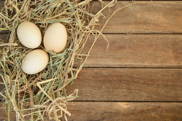 Oeuf dans le nid de foin sur le vieux fond de table en bois