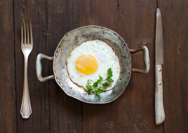 Photo Œuf frit dans une vieille poêle avec fourchette et couteau