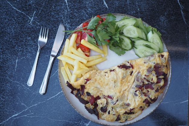 Un œuf frit mélangé à une saucisse servi avec des frites et de la salade