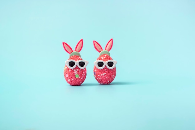 Oeuf de Pâques coloré avec oreilles de lapin et lunettes de soleil sur fond bleu Modèle de maquette de bannière de vente avec espace de copie