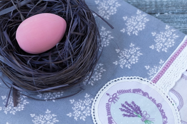 Oeuf de Pâques dans un nid, serviette sur un bois.