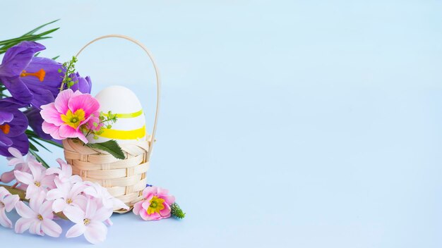 Oeuf de Pâques dans un panier décoré de fleurs