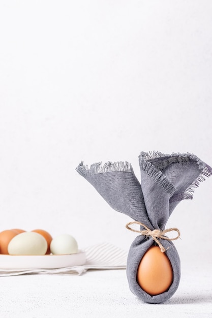 Oeuf de Pâques décoré d'une serviette en forme de lapin sur fond de béton blanc