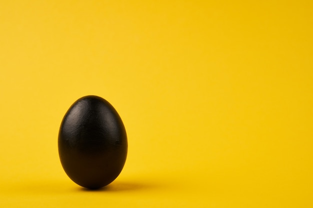 Oeuf de Pâques noir coloré sur fond jaune vif