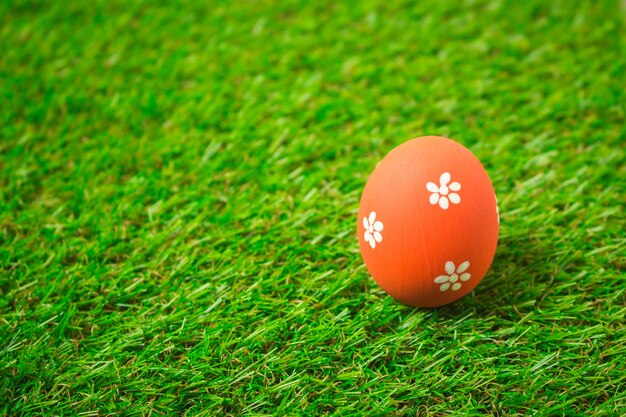 Oeuf de Pâques orange sur l'herbe verte.