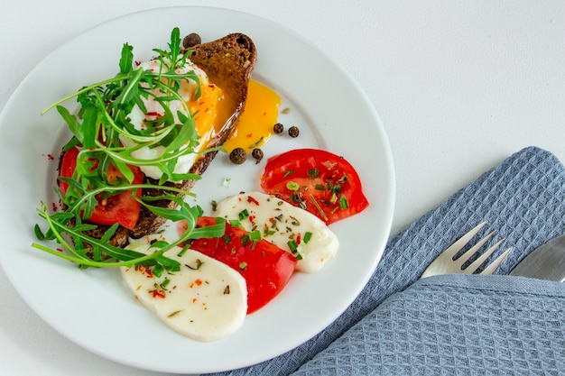 oeuf poché sur pain noir avec tomates mozzarella et roquette