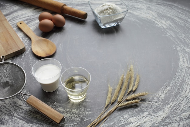 Oeuf De Poule, Farine, Huile D'olive, Lait, épis De Blé, Ustensile De Cuisine Sur Fond De Tableau Gris.