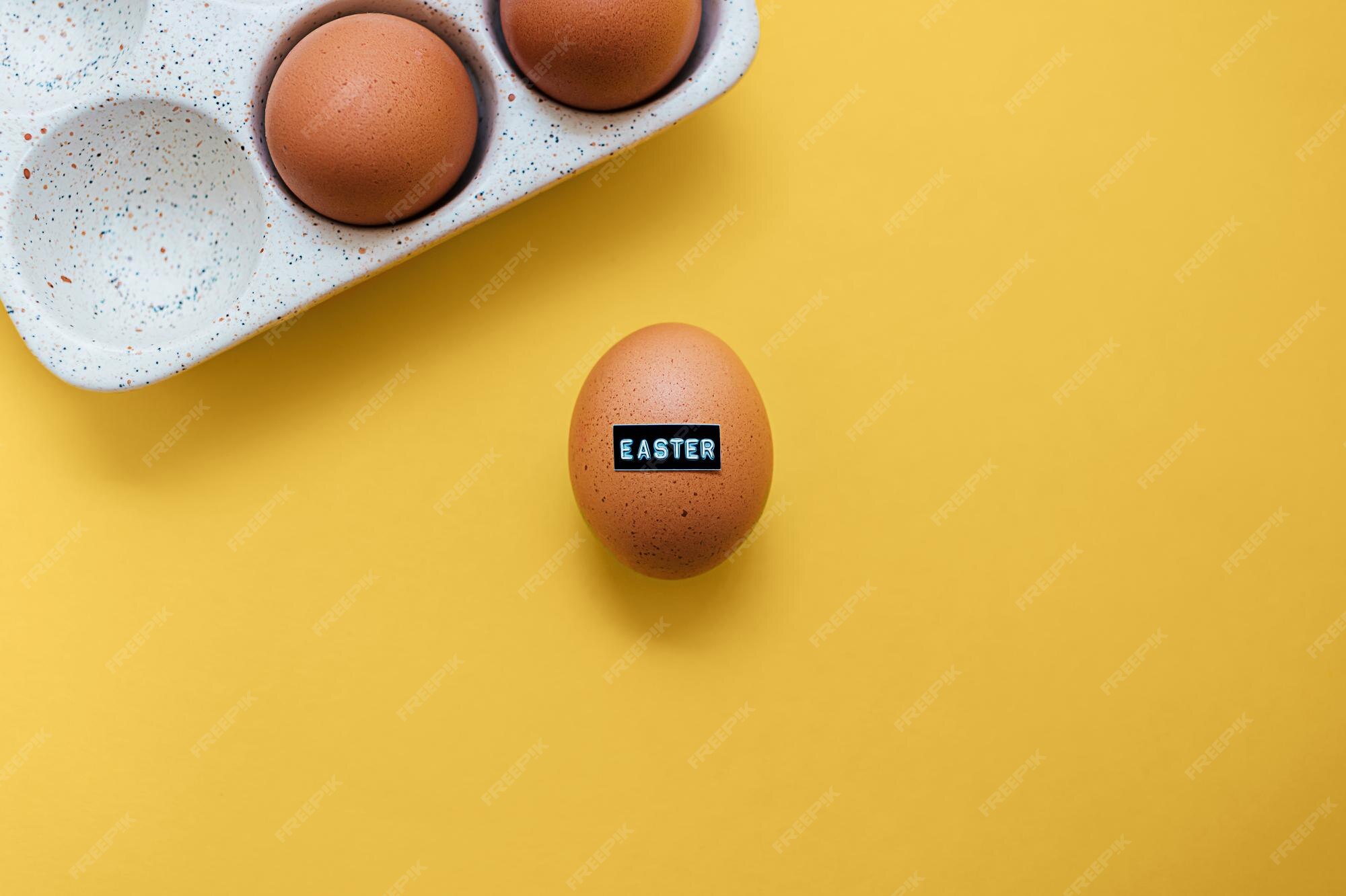 Oeuf De Poulet Cru Brun Avec Mot En Relief Paques Et Oeufs Dans Un Plateau De Rangement En Ceramique Sur Fond Jaune Avec Espace De Copie Decor De Vacances Creatif Et Carte