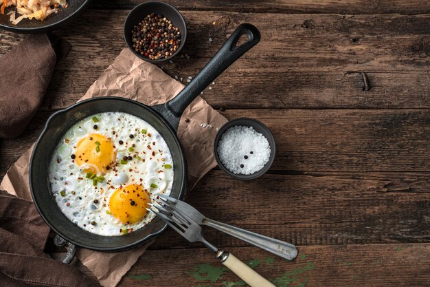 Oeufs au plat sur un fond en bois. Vue de dessus, avec espace pour copier. Le concept de cuisine.