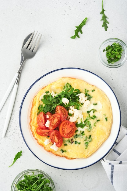 Oeufs au plat pour le petit-déjeuner Omelette rustique ou frittatas aux oignons verts fromage mozzarella roquette verte et tomates sur fond de pierre claire Concept d'aliments sains Espace de copie Vue de dessus Maquette