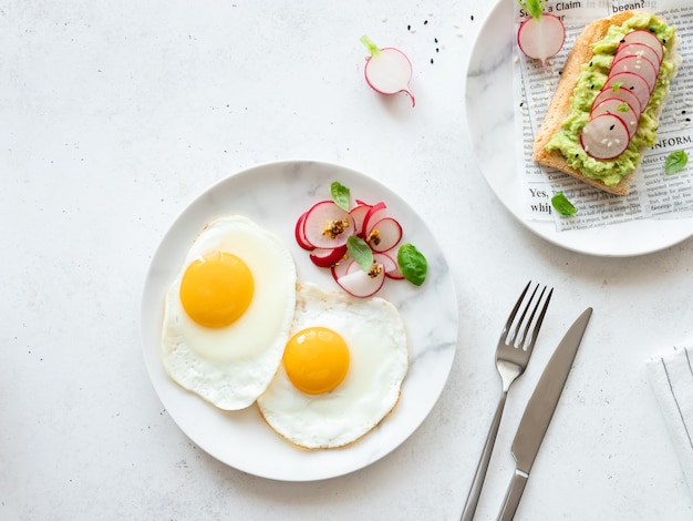 Oeufs au plat et toasts à l'avocat sur assiettes