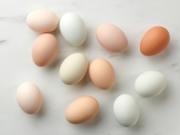 Oeufs bio colorés crus frais sur la table de la cuisine, vue de dessus