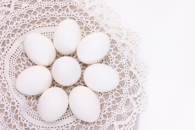 Oeufs blancs biologiques de poulet fraîcheur nutrition saine sur un sac brun et une belle serviette en tricot blanc en forme de fleur.
