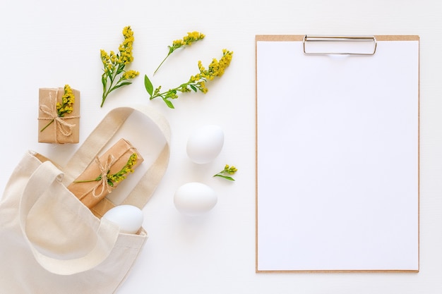 Oeufs blancs, fleurs jaunes, cadeaux artisanaux voler hors sac textile et presse-papiers avec du papier sur blanc