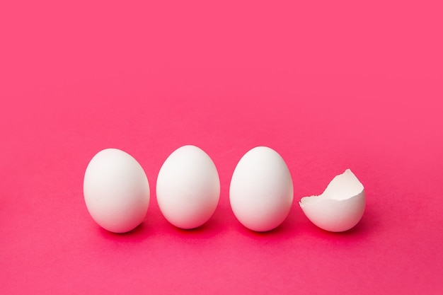 Oeufs blancs près de la coquille cassée sur la table rose