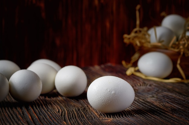 Oeufs blancs sur une table en bois, oeufs dans un bol en bois en arrière-plan. Fermer. Discret.