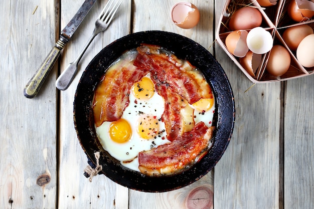 Oeufs brouillés au bacon dans une poêle sur la table.