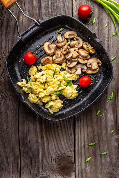 Oeufs brouillés aux oignons et champignons dans une poêle à frire, image verticale, place pour le texte.