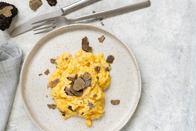 Oeufs brouillés aux truffes noires fraîches d'Italie servis dans une assiette vue de dessus petit-déjeuner gastronomique