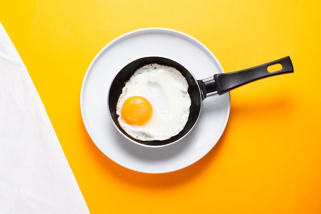 Oeufs brouillés et frits d'un oeuf dans une petite casserole sur fond jaune