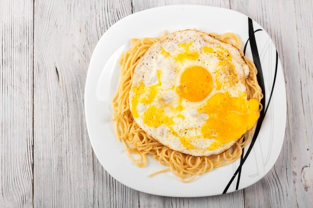 Oeufs brouillés avec des pâtes sur une plaque blanche