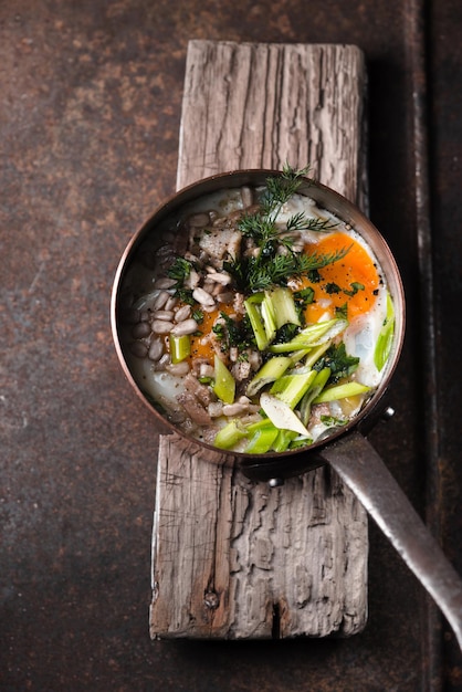 Oeufs brouillés avec des verts dans la marmite en cuivre sur la vue de dessus de table en métal